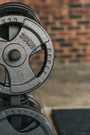 Detailed view of a 20kg weight plate on a gym rack with a blurry brick wall background.